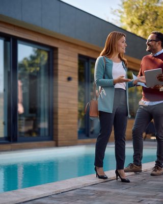 Happy woman talking to real estate agent while buying new house with her husband. Copy space.