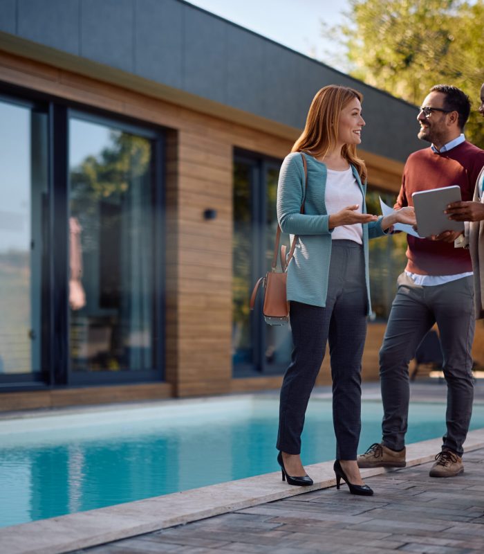 Happy woman talking to real estate agent while buying new house with her husband. Copy space.